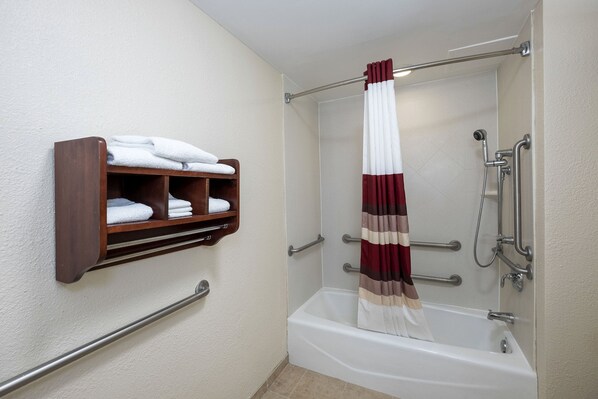 A bathroom with a white bathtub, a wooden towel rack with folded towels, and a shower curtain. - Red Roof Inn Meriden (Meriden)