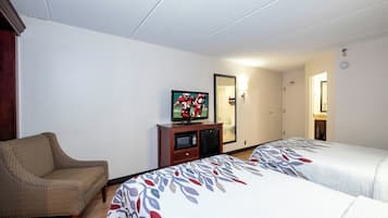 Quarto de hotel com duas camas, televisão, um pequeno armário e uma cadeira.