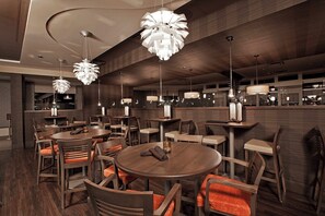 A modern restaurant interior with round tables, chairs, and unique pendant lighting. - Holiday Inn & Suites Windsor Ambassador Bridge by IHG (Windsor)