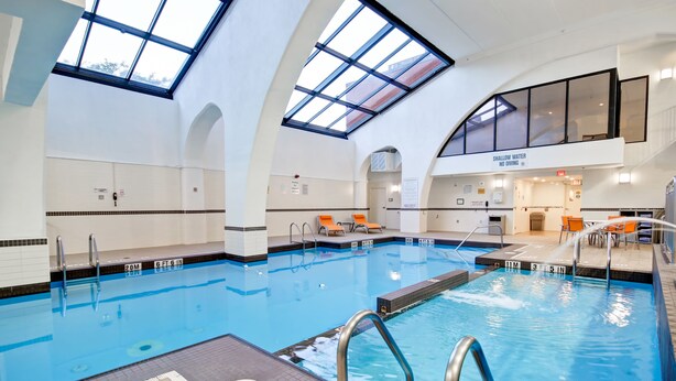 Une piscine intérieure dotée de marquages clairs, d’une verrière et d’un panneau indiquant la zone où l’eau est peu profonde.
