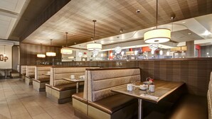Un intérieur de restaurant moderne avec des banquettes, des luminaires suspendus et un espace bar.