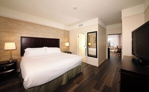 A hotel room with a large bed, bedside lamps, a flat-screen TV, and a wooden floor. - Holiday Inn & Suites Windsor Ambassador Bridge by IHG (Windsor)