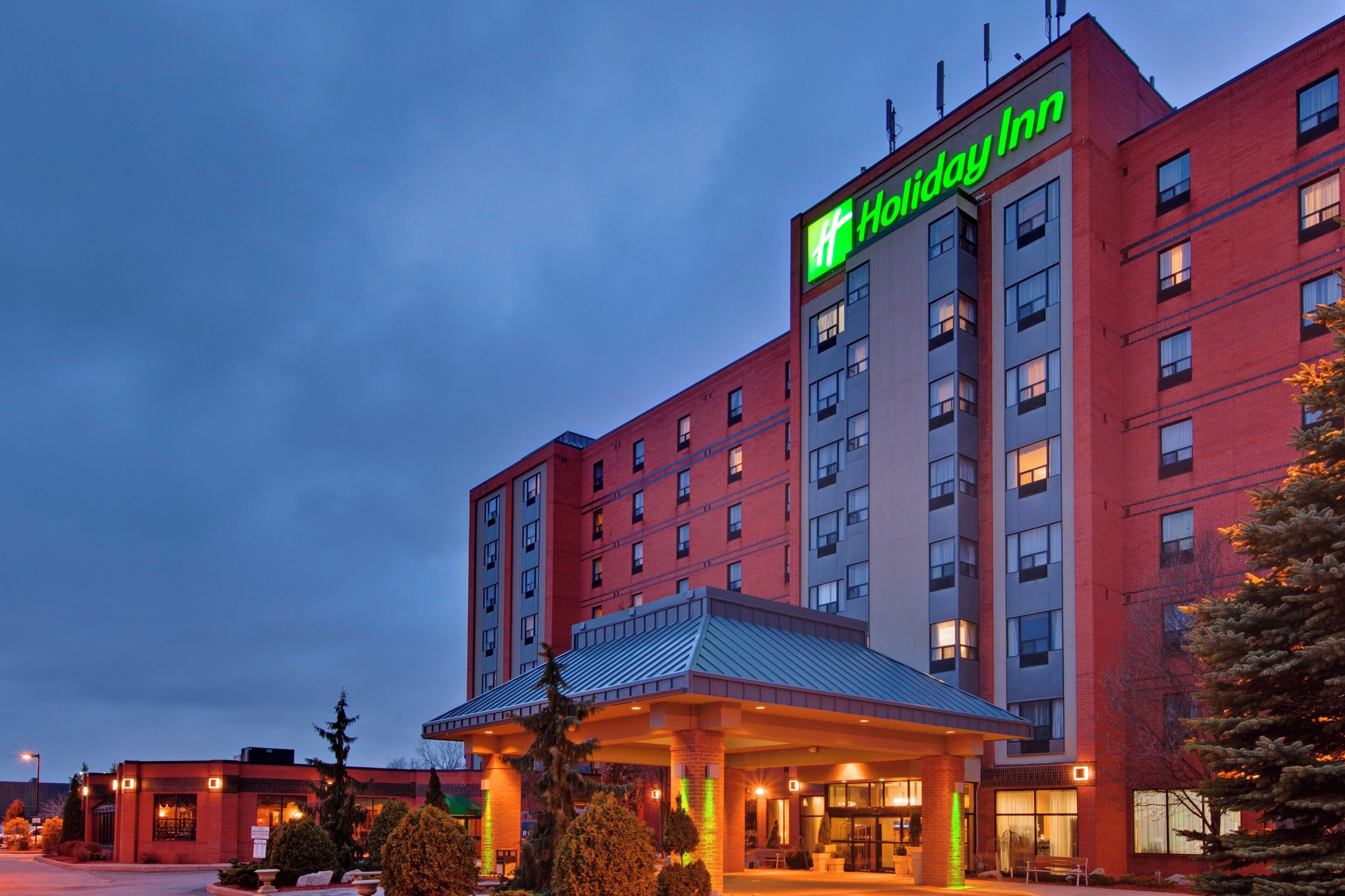 A Holiday Inn hotel with a prominent sign, a covered entrance, and a brick facade.
