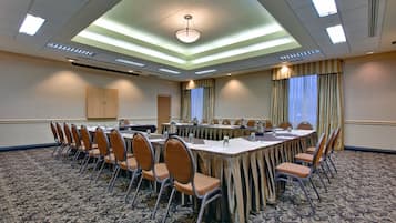Un salón de conferencias con una mesa larga, sillas y piso alfombrado.