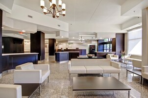 Un moderno vestíbulo de hotel con recepción, zona de estar y una cocina al fondo.