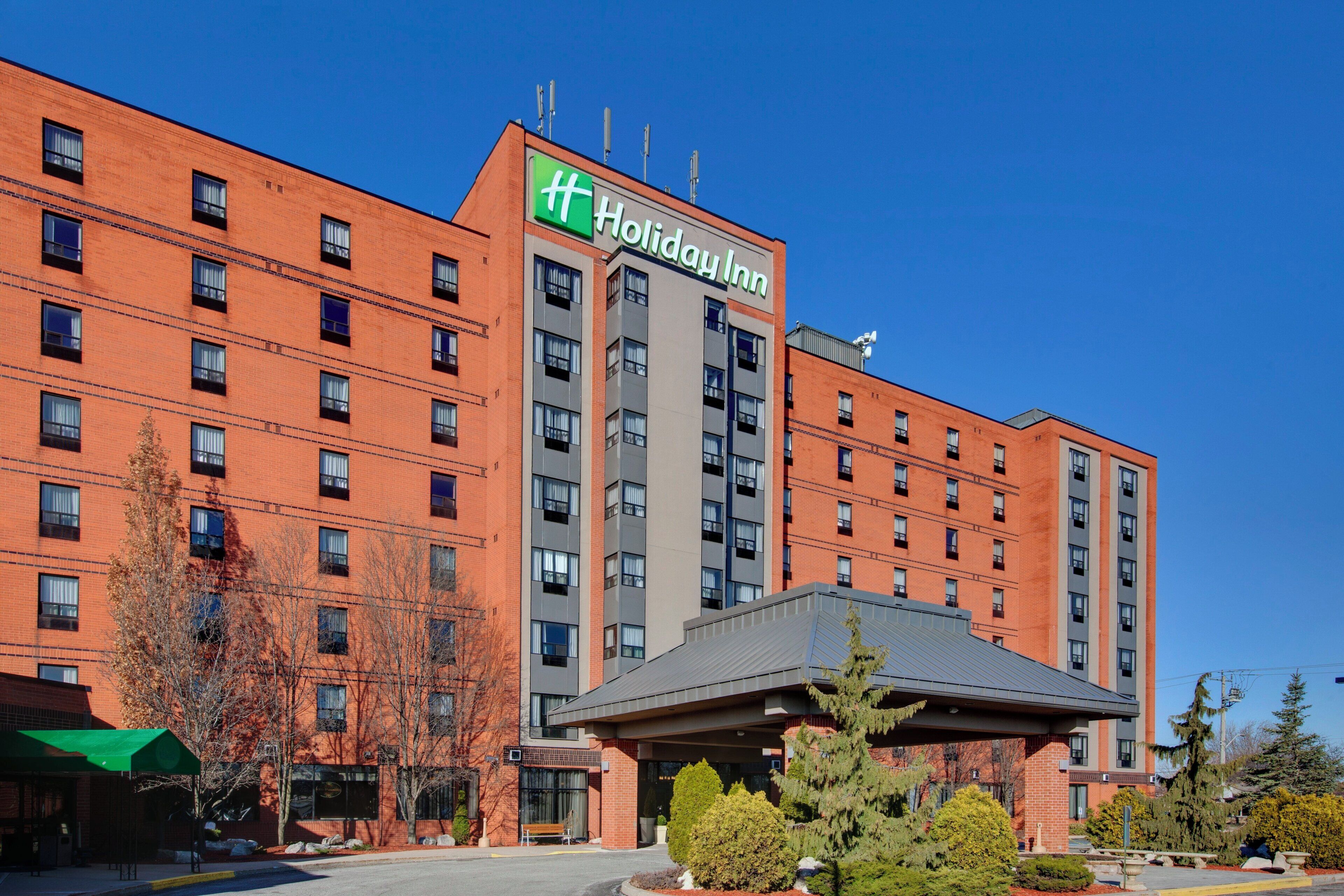 A Holiday Inn hotel with a brick facade, multiple floors, and a covered entrance area.