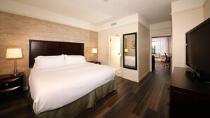 Une chambre d’hôtel avec un grand lit, deux tables de chevet avec des lampes, un téléviseur à écran plat et un miroir.