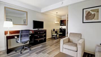 A hotel room with a desk, chair, television, and a sofa.
