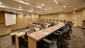 Une salle de conférence à l’agencement incurvé, dotée de plusieurs tables et de chaises.