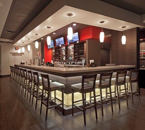 A bar area with multiple seating options and a television screen. - Holiday Inn & Suites Windsor Ambassador Bridge by IHG (Windsor)