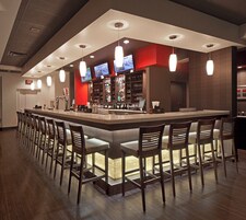 Zona de bar con diversas opciones de asiento y una pantalla de televisión.