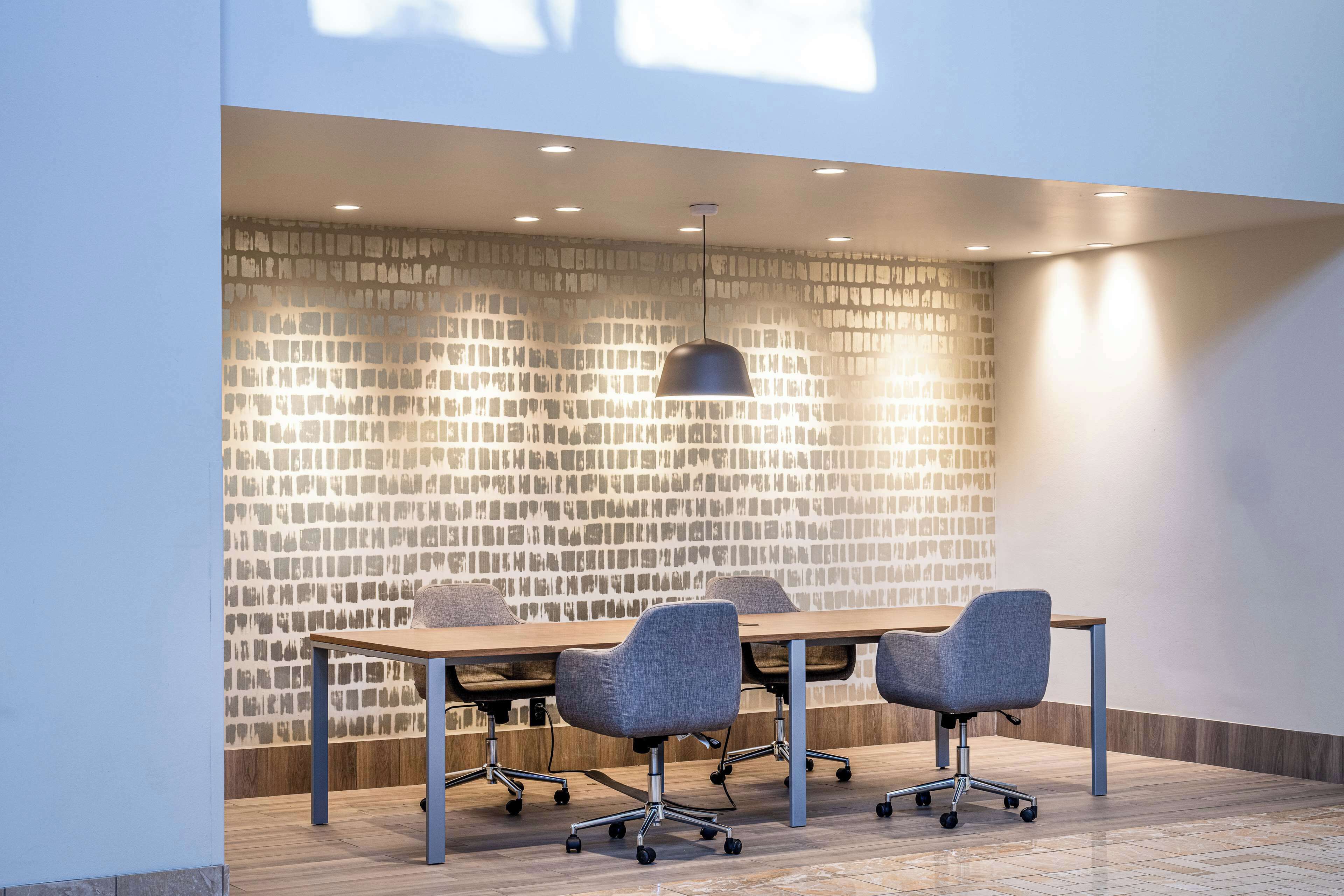 Une salle de conférence avec une longue table, quatre chaises et un luminaire suspendu moderne.