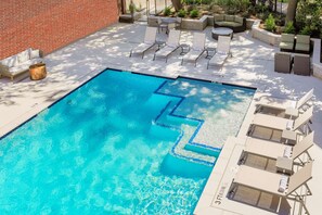 Relax by the pool surrounded by lounge chairs and a small table.