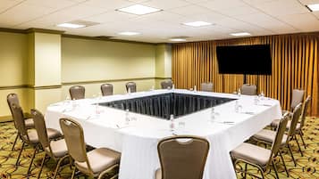 Une salle de conférence dotée d’une grande table ovale, de nombreuses chaises et d’un téléviseur à écran plat fixé au mur.