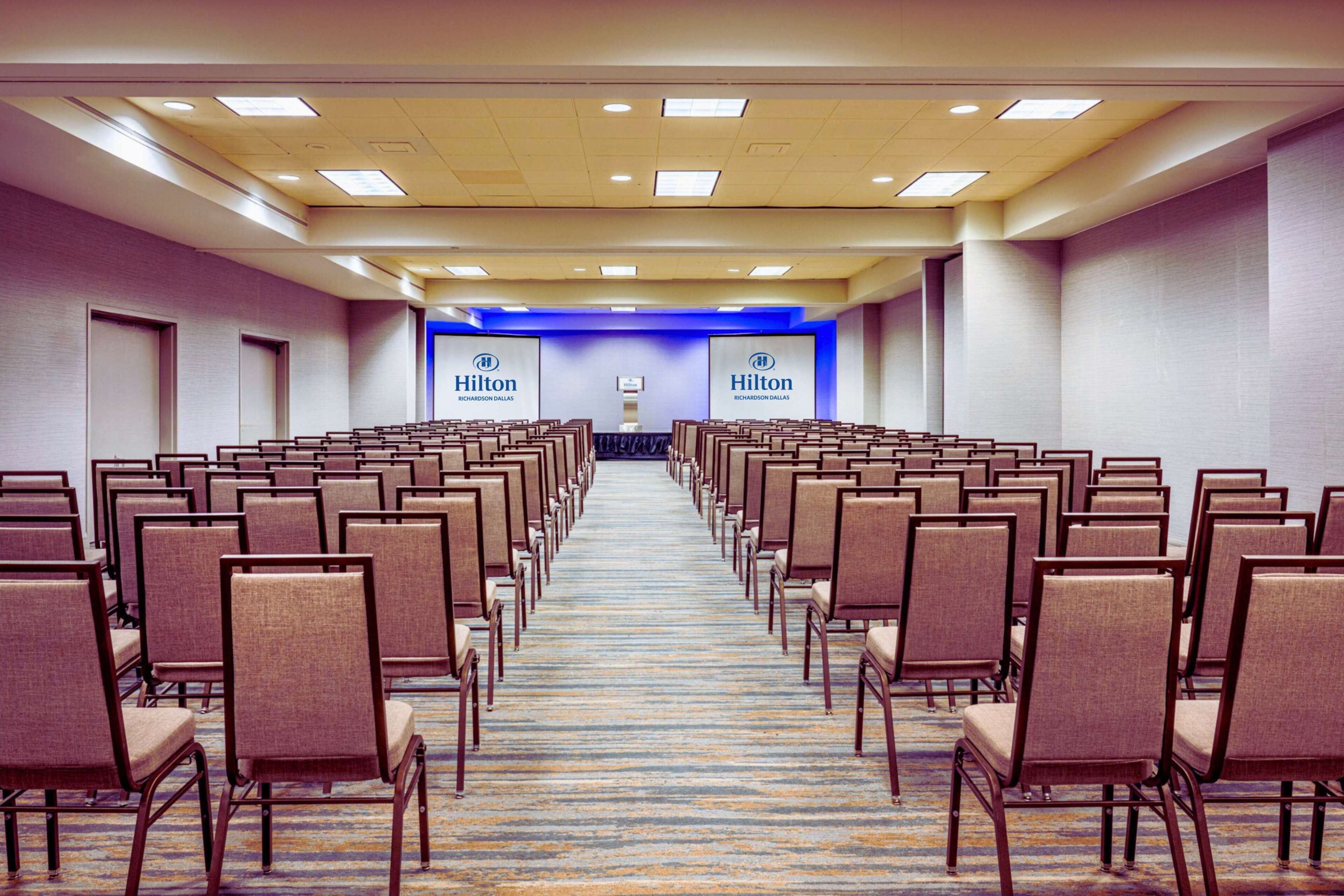 A hotel conference room with rows of chairs and a carpeted floor.