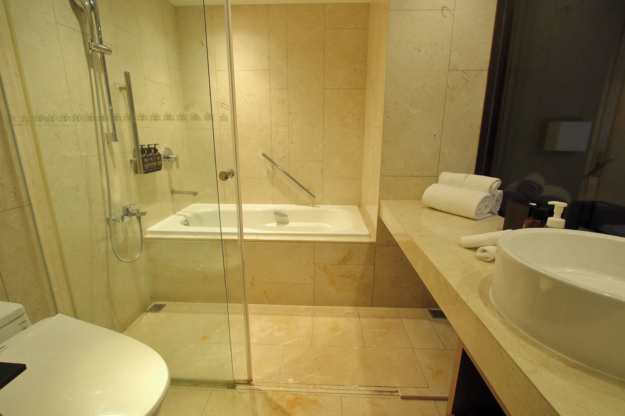 A bathroom with a glass-enclosed shower, a bathtub, a large sink, and a toilet.