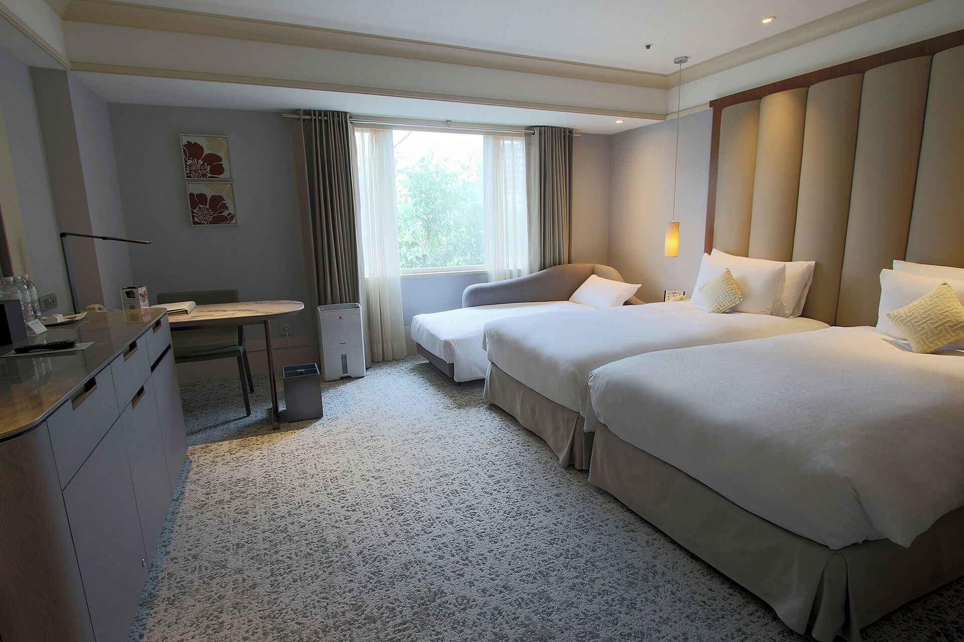 A hotel room with two beds, a desk, a chair, and a window with curtains.