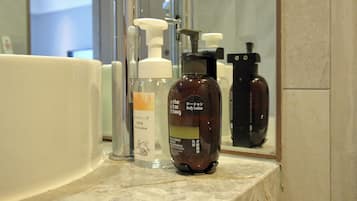 A bathroom with a sink, a mirror, and various toiletries including a body lotion bottle.