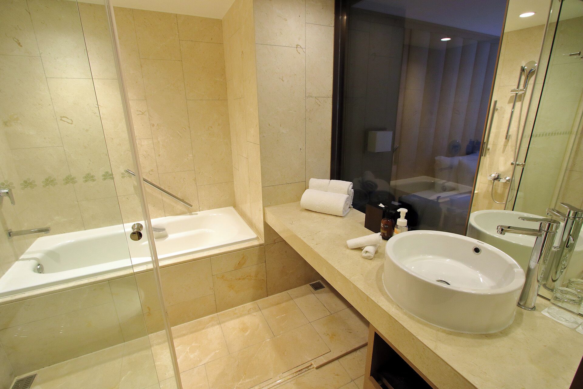 A modern bathroom with a glass-enclosed shower, a large bathtub, and a vanity with a sink and mirror.