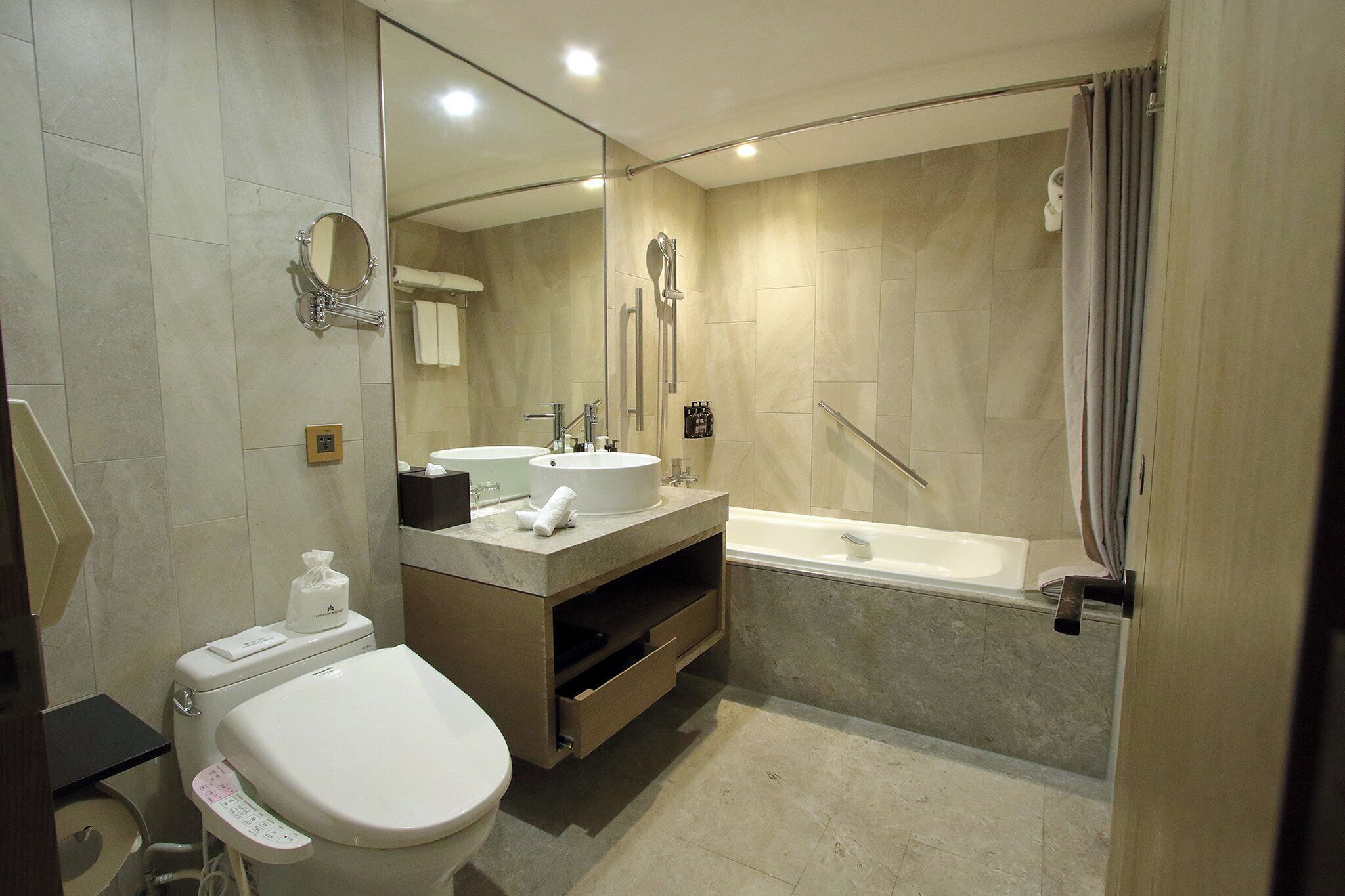 A modern bathroom with a toilet, sink, vanity, and bathtub.