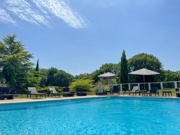 Una piscina al aire libre de temporada, tumbonas