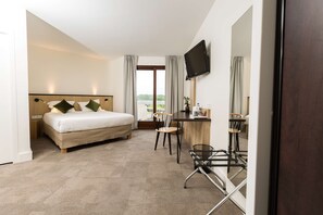 Une chambre d’hôtel équipée d’un lit, d’un bureau, d’une chaise, d’une télévision et offrant une vue sur l’extérieur.