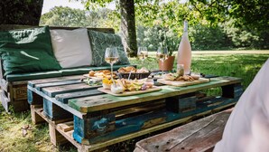 Un coin pique-nique aménagé avec une table en bois, un canapé vert et un banc.