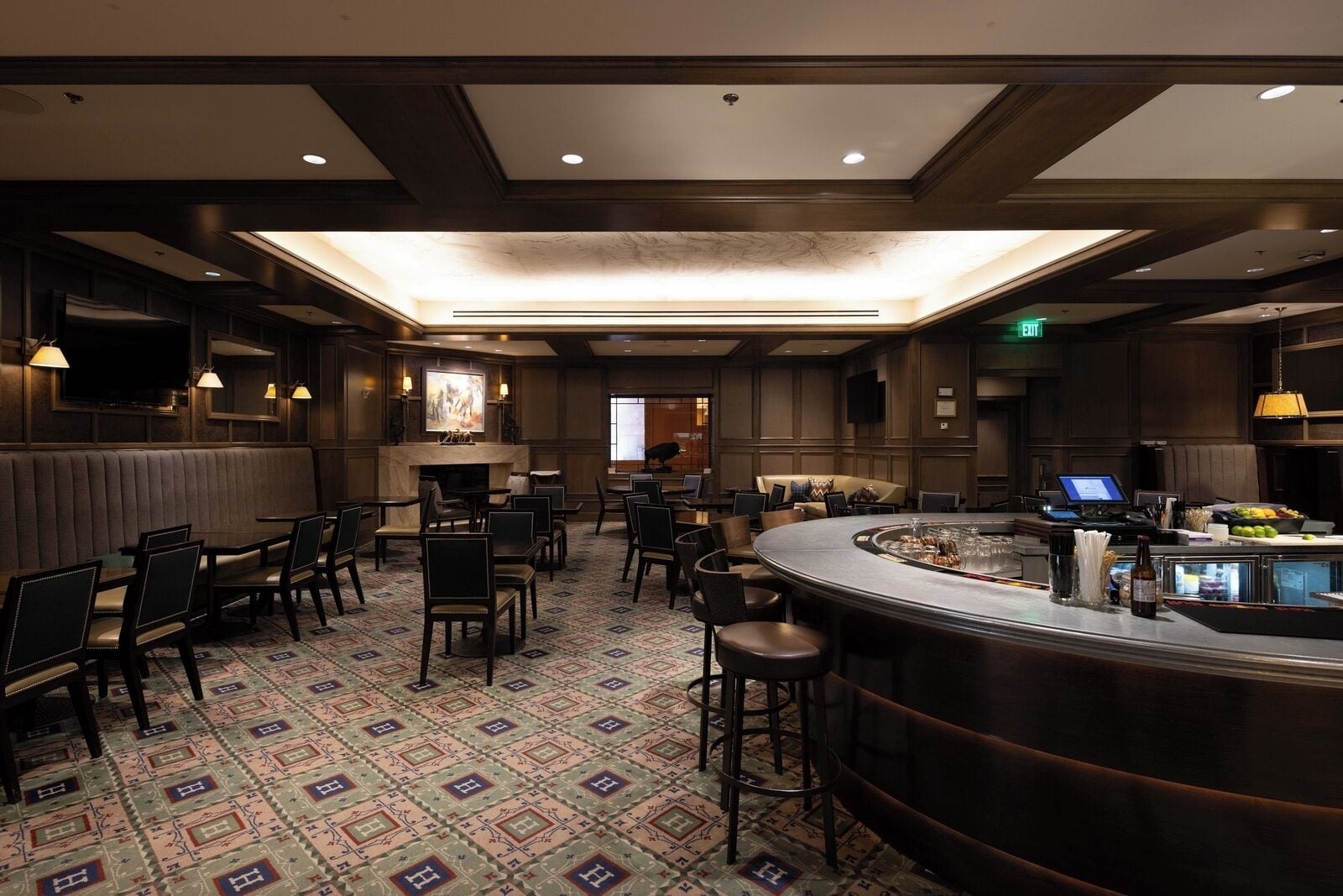 Un hall de hotel con zona de bar, distribución de asientos y chimenea.