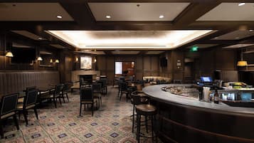 A hotel lobby with a bar area, seating arrangements, and a fireplace.