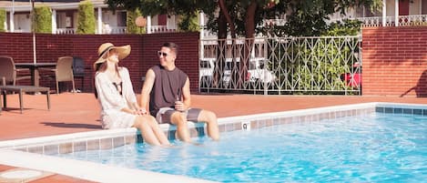 Une piscine avec deux personnes assises au bord.