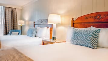 Une chambre d’hôtel avec deux lits, une table de chevet avec une lampe et une fenêtre avec des rideaux.