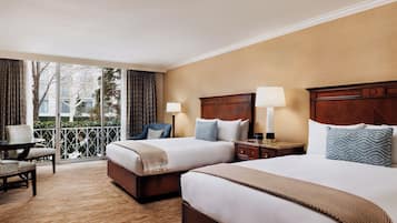 Une chambre d’hôtel avec deux lits, un balcon offrant une vue, un bureau et une chaise.