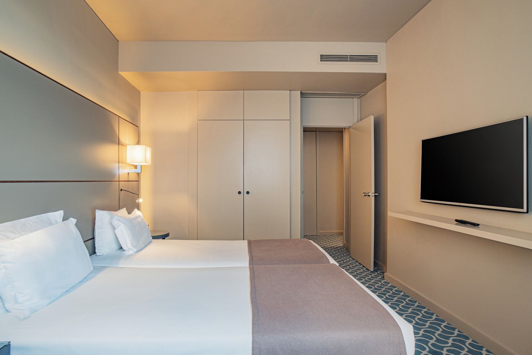 Une chambre d’hôtel avec un lit, une télévision, une armoire et une porte de salle de bain.