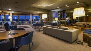 A modern lounge area with a sofa, chairs, a coffee table, and a bookshelf. - Hotel Dom Henrique Downtown (Porto)