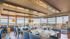 A restaurant with tables set for dining, large windows offering a city view, and a modern interior design. - Hotel Dom Henrique Downtown (Porto)