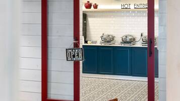 Uma cozinha moderna com armários azuis, teto de madeira e uma placa com a inscrição 'HOT ENTRE'.