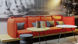 A modern lounge area with a red sofa, a round table, and a decorative lamp. - ibis Poitiers Beaulieu (Poitiers)