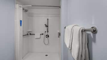 A shower with a handheld showerhead, a towel rack with a towel, and a small shelf with toiletries.