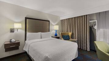 Habitación de hotel con una cama grande, dos mesitas de noche, una lámpara, una silla y un armario.