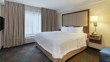 A hotel room with a large bed, a bedside table with a lamp, a TV, and a window with curtains.