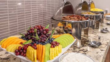 Un bufé con diversas frutas, quesos y embutidos.