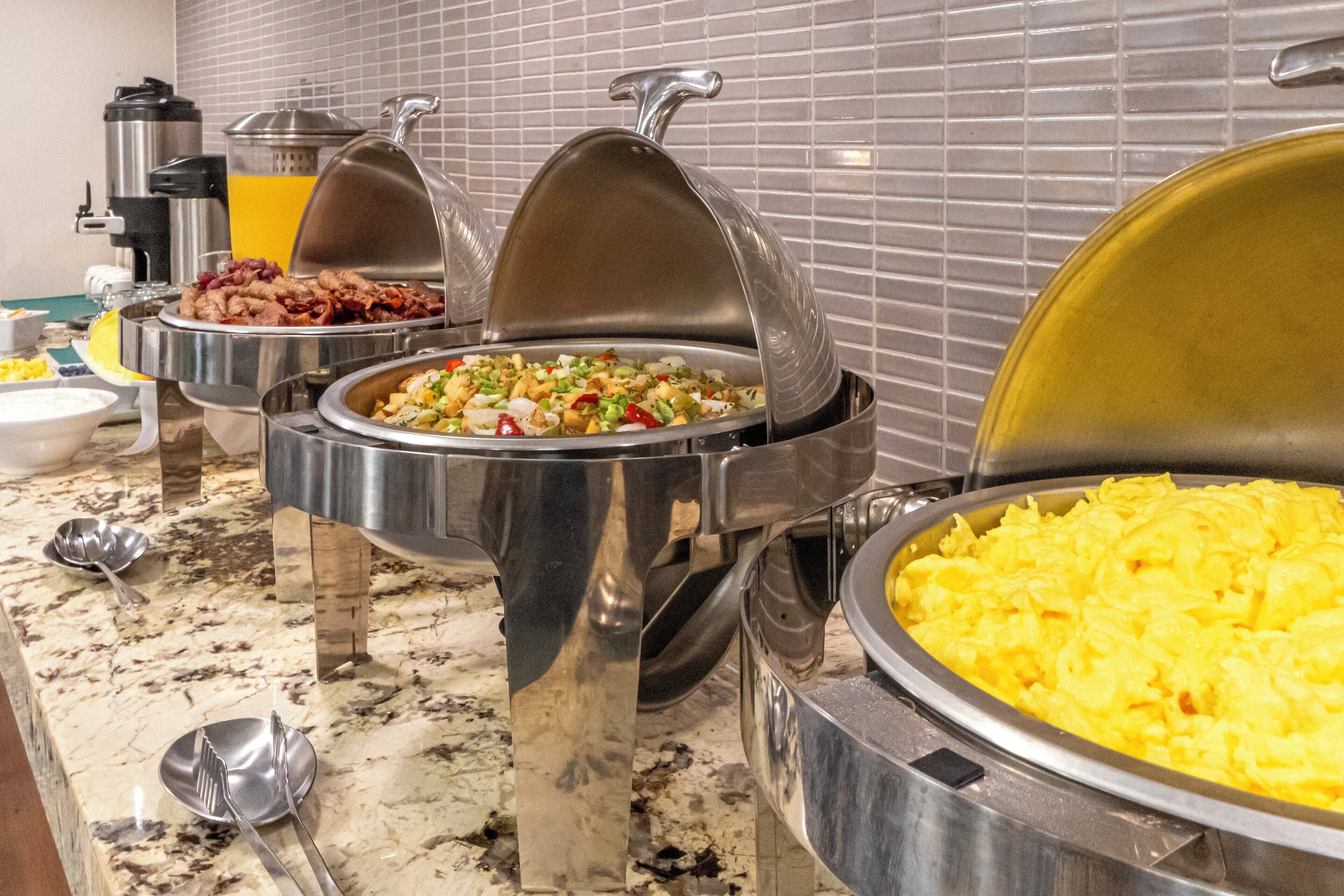 A buffet with various food items, including scrambled eggs, a salad, and other dishes, served on a marble countertop.