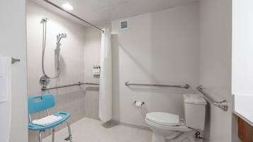 A bathroom with a shower, toilet, and a wheelchair-accessible bench.