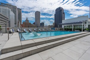 A rooftop pool with steps leading down to the water, surrounded by city buildings.