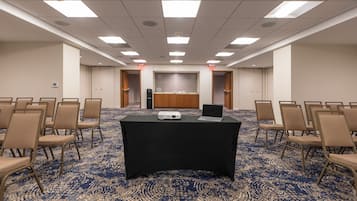 A conference room with a black table, chairs, a projector, and a tiled backsplash.
