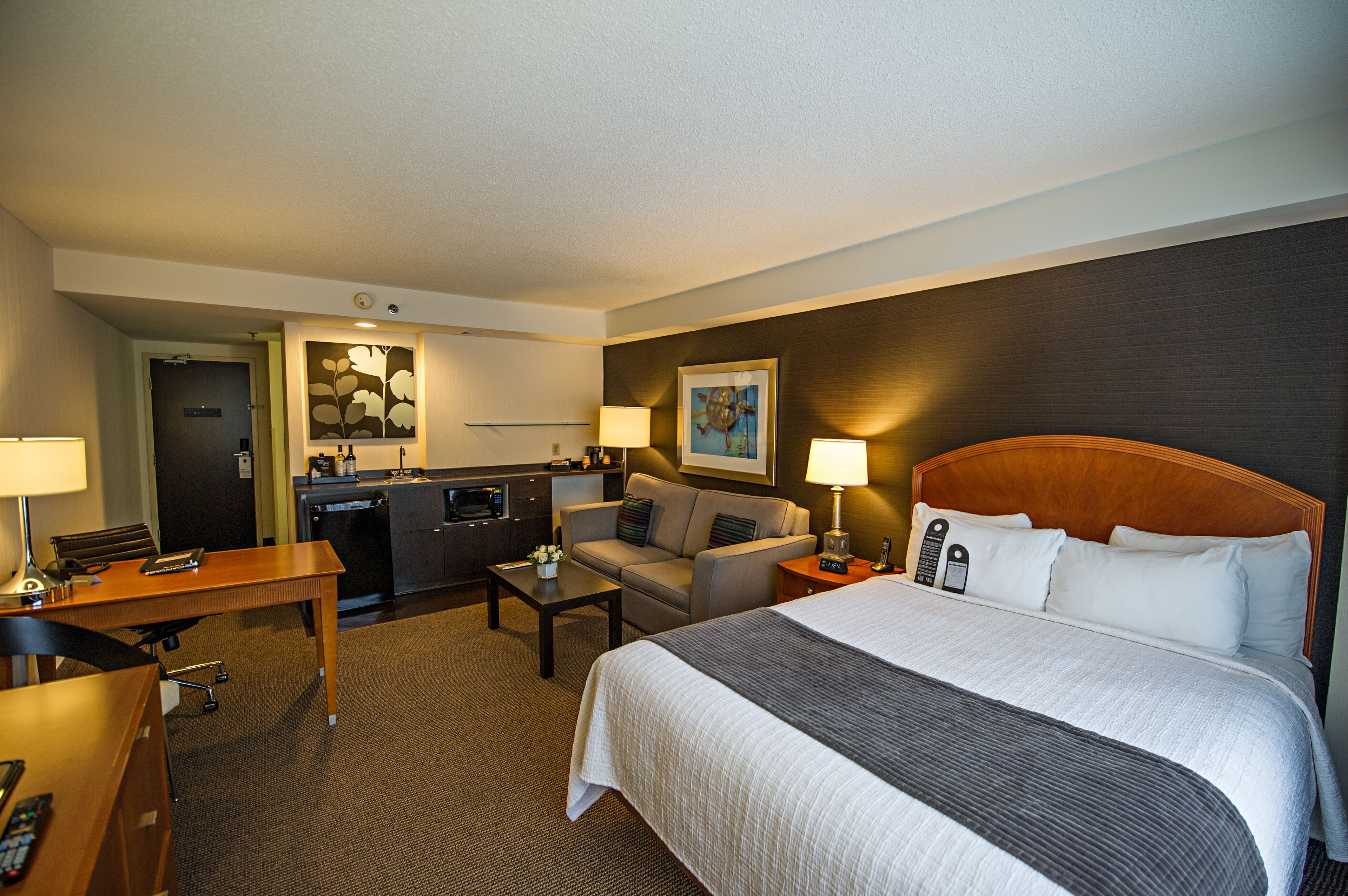 Une chambre d’hôtel avec un grand lit, un bureau, un canapé, une table basse et une kitchenette.