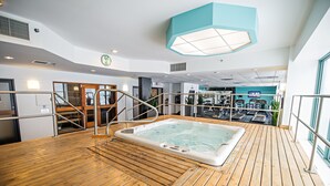A wooden deck with a hot tub, indoor gym, and a large window. - Cambridge Suites Hotel (Halifax)