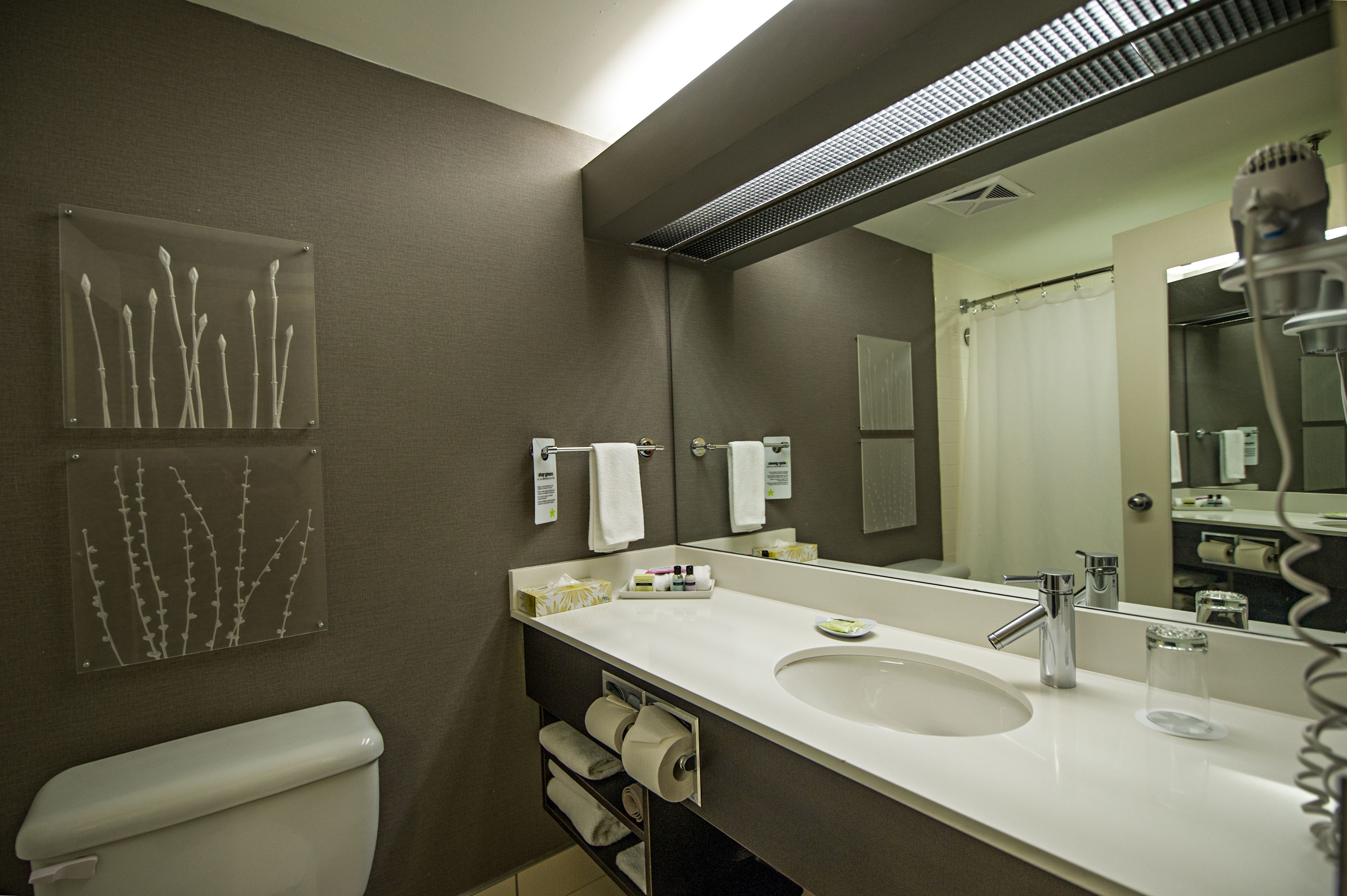 A modern bathroom with a large mirror, a sink, and a toilet.