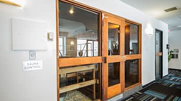 A hallway with a sauna control sign, a wooden-framed window, and a striped carpet.