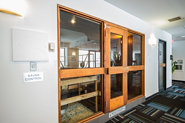 A hallway with a sauna control sign, a wooden-framed window, and a striped carpet. - Cambridge Suites Hotel (Halifax)